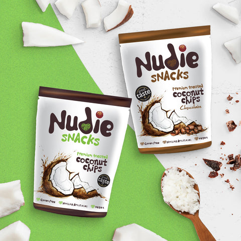 Nudie Snacks Toasted Coconut Chips surrounded by coconut pieces and chocolate